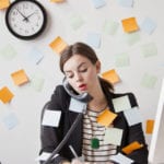 Busy season: Studio shot of young woman working in office covered with adhesive notes