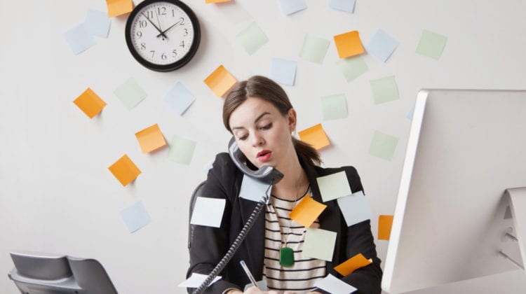 Busy season: Studio shot of young woman working in office covered with adhesive notes
